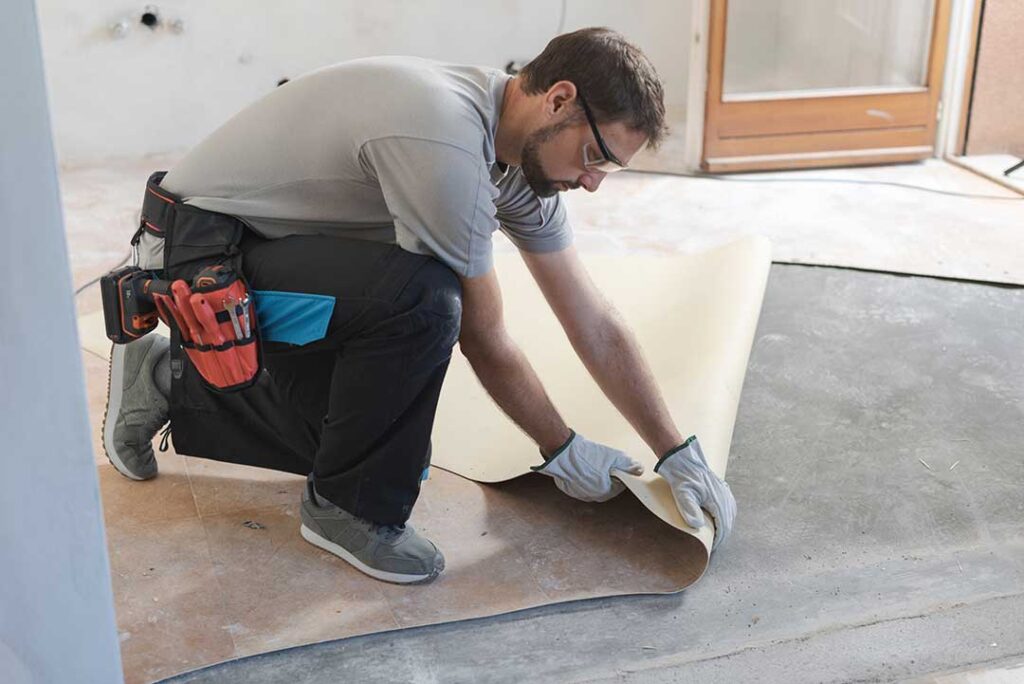 A homeowner comparing flooring samples in a residential living room with natural daylight.