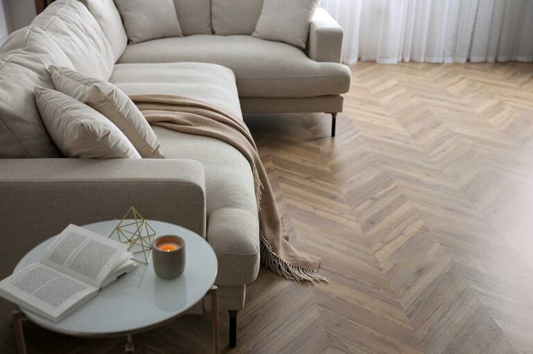 A person installing interlocking laminate flooring boards on a clean underlayment with tools nearby.