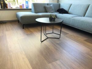 A homeowner wiping up a spilled drink from vinyl plank flooring in a bright living room.
